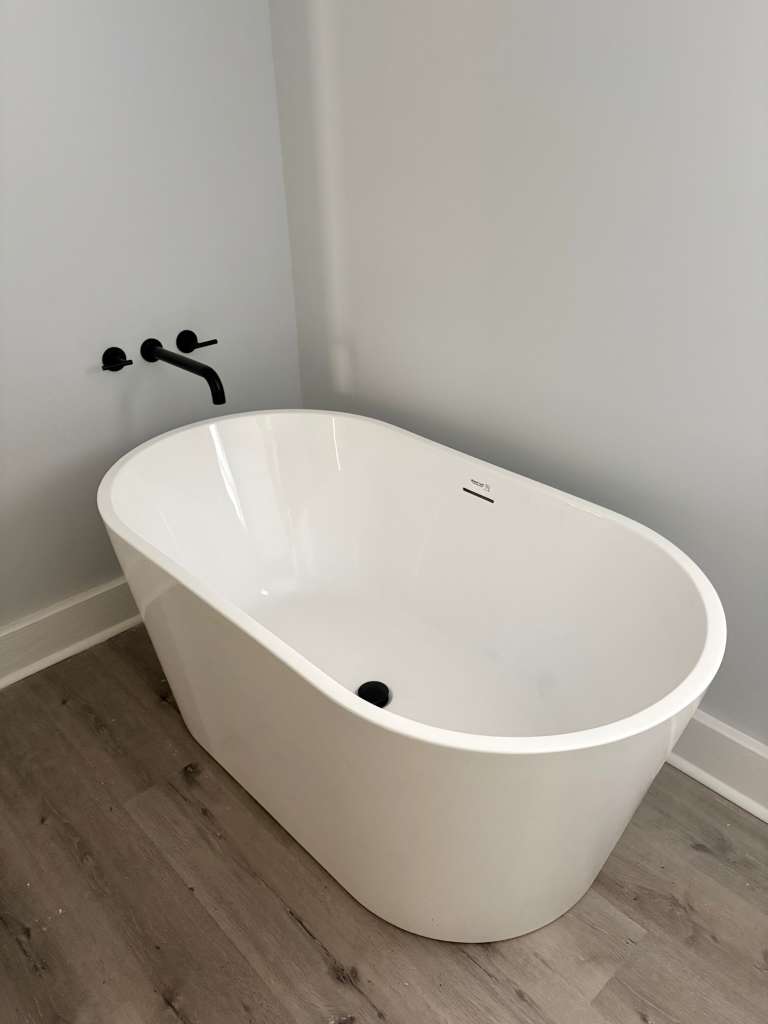 Freestanding soaking tub with matte black wall-mount faucet