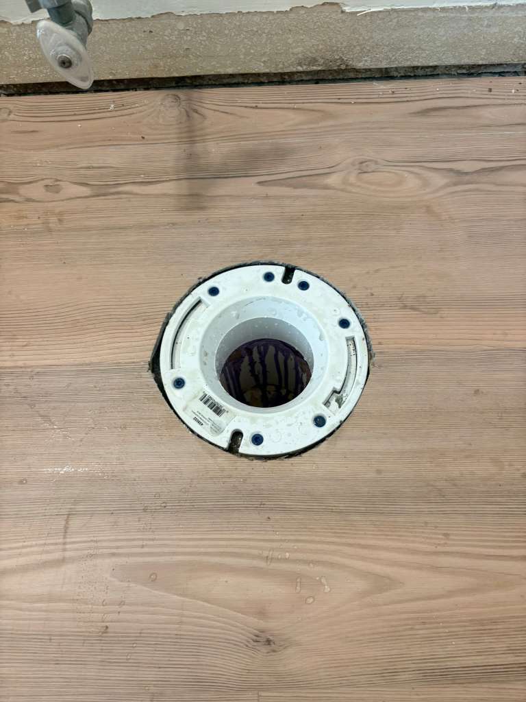 New PVC toilet flange installed on subfloor